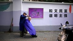 A resident gets a haircut by the roadside in Shanghai, China November 27, 2017. REUTERS/Aly Song