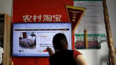 A customer points at a screen displaying a website of Alibaba's Taobao at a rural service centre in Yuzhao Village, Tonglu, Zhejiang province, China, July 20, 2015.  REUTERS/Aly Song 