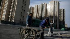 FILE PHOTO: Men work near residential apartment blocks under construction on the outskirts of Beijing, China, November 29, 2017.  REUTERS/Thomas Peter/File Photo