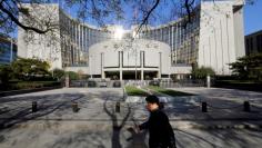 A man walks past the headquarters of the People's Bank of China (PBOC), the central bank, in Beijing November 20, 2013. REUTERS/Jason Lee