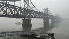 FILE PHOTO: Trucks move across the bridge linking North Korea with the Chinese border city of Dandong in this March 3, 2016 file photo.    REUTERS/Megha Rajagopalan/File Photo