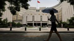 FILE PHOTO: A woman walks past the headquarters of the People's Bank of China (PBOC), the central bank, in Beijing, June 21, 2013.   REUTERS/Jason Lee/File Photo