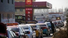 FILE PHOTO: Cars line up at a filling station for liquid natural gas (LNG), one of a few that is open for business, in Baoding, Hebei province, China, December 5, 2017.  Picture taken December 5, 2017.  REUTERS/Thomas Peter