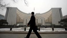 FILE PHOTO: A man walks past the headquarters of the central bank of the People's Republic of China in Beijing