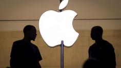 Customers stand beneath an Apple logo at the Apple store in New York City's Grand Central station in New York City