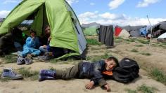 A boy sleeps outside a tent at a makeshift camp for refugees and migrants at the Greek-Macedonian border near the village of Idomeni, Greece, May 5, 2016. REUTERS/Alexandros Avramidis