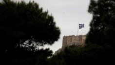 FILE PHOTO: A Greek national flag waves over people visiting the Acropolis hill in Athens