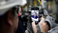 An employee uses a mobile phone to make of picture of French President Emmanuel Macron as he visits Toyota's automobile manufacturing plant in Onnaing, France, January 22, 2018.  REUTERS/Pascal Rossignol