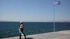 A man walks among seaside as a greek flag flutters at Faliro suburb near Athens, Greece, September 1, 2017. REUTERS/Costas Baltas 