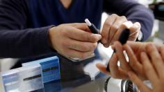 FILE PHOTO: A customer prepares to try a Philip Morris' "iQOS" smokeless tobacco at an iQOS store in Tokyo