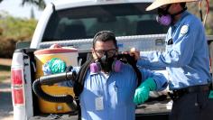 Robert Murillo gets help putting on his spraying apparatus as San Diego County officials hand spray a two block area to help prevent the mosquito-borne transmission of the Zika virus in San Diego