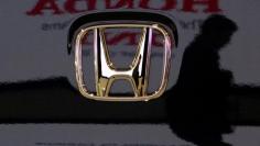 A visitor and the logo of Honda Motor Co are reflected on a Honda car at the company's headquarters in Tokyo January 30, 2009.      REUTERS/Toru Hanai/File Photo  