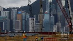 Workers at work at West Kowloon Terminus, under construction for the Guangzhou-Shenzhen-Hong Kong Express Rail Link, with a backdrop of the financial district in Hong Kong, China July 21, 2017.   REUTERS/Bobby Yip