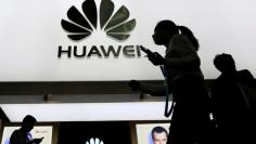 FILE PHOTO: People walk past a sign board of Huawei at CES (Consumer Electronics Show) Asia 2016 in Shanghai, China May 12, 2016. REUTERS/Aly Song/File Photo 