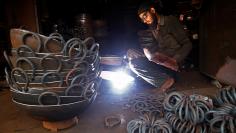 A worker welds handles on a deep frying pan at an industrial unit in Mumbai, India, January 12, 2018. REUTERS/Shailesh Andrade