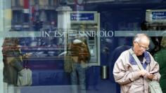 A man stands outside a building as people use Intesa Sanpaolo automated teller machines (ATMs) in Milan October 1, 2013.  REUTERS/Stefano Rellandini 