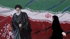 Woman walks past a painting of Iran's late leader Ayatollah Ruhollah Khomeini in Tehran