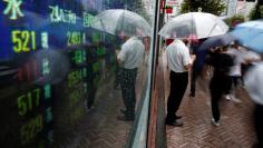 File Photo - A man stands next to an electronic board showing stock prices in Tokyo, Japan, August 18, 2016. REUTERS/Kim Kyung-Hoon 