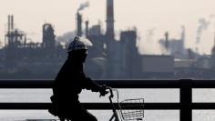 FILE PHOTO: A worker cycles near a factory at the Keihin industrial zone in Kawasaki, Japan