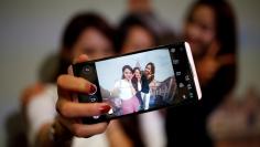 Models pose for photographs with a LG electronics' new V20 premium smartphone during its unveiling ceremony in Seoul