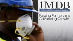 FILE PHOTO: A construction worker talks on the phone in front of a 1Malaysia Development Berhad (1MDB) billboard at the Tun Razak Exchange development in Kuala Lumpur, Malaysia, February 3, 2016.   REUTERS/Olivia Harris/File Photo