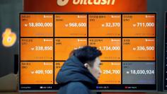 A man walks past an electric board showing exchange rates of various cryptocurrencies including Bitcoin (top L) at a cryptocurrencies exchange in Seoul, South Korea December 13, 2017.  REUTERS/Kim Hong-Ji 