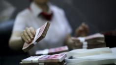 An employee of the Industrial and Commercial Bank of China Ltd (ICBC) counts money at one of the bank's branches at the Shanghai Free Trade Zone in Pudong district, in Shanghai September 24, 2014. REUTERS/Carlos Barria 