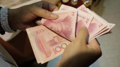 A woman counts Chinese yuan notes at a market in Beijing, July 1, 2013. REUTERS/Jason Lee 