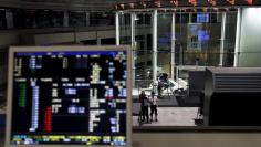 A videographer films an electronic board showing the Japan's Nikkei average and related indexes is seen next to a computer showing the market indexes at the Tokyo Stock Exchange (TSE) in Tokyo, Japan, July 9, 2015.  REUTERS/Yuya Shino