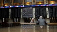 FILE PHOTO: Traders talk as they are seen near screens at Madrid's bourse, Spain, July 6, 2015.   REUTERS/Juan Medina