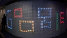 FILE PHOTO: A man checks his mobile phone next to an illuminated panel at Google stand during the Mobile World Congress in Barcelona, Spain, March 1, 2017. REUTERS/Paul Hanna/File Photo      