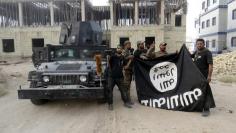 Iraqi security forces hold an Islamist State flag which they pulled down at the University of Anbar, in Anbar province July 26, 2015.  REUTERS/Stringer 