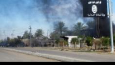 Smoke raises behind an Islamic State flag after Iraqi security forces and Shiite fighters took control of Saadiya in Diyala province from Islamist State militants, November 24, 2014. REUTERS/Stringer 