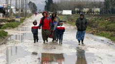 Syrian refugees walk along a makeshift settlement in Bar Elias in the Bekaa valley January 5, 2015. REUTERS/Mohamed Azakir 