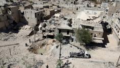 A general view shows a hole in the ground filled with water in a damaged site after airstrikes on the rebel held Tariq al-Bab neighbourhood of Aleppo