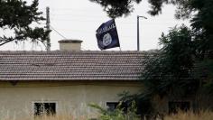 An Islamic State flag flies over the custom office of Syria's Jarablus border gate as it is pictured from the Turkish town of Karkamis, in Gaziantep province, Turkey August 1, 2015. REUTERS/Murad Sezer 