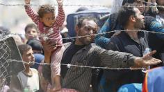 A Syrian refugee holds onto his daughter as he waits to cross into Turkey at Akcakale border gate in Sanliurfa province, Turkey, June 15, 2015. REUTERS/Umit Bektas 