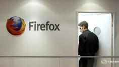 A man is seen next to a Firefox logo at a Mozilla stand during the Mobile World Congress in Barcelona, February 28, 2013. REUTERS/Albert Gea/Files 