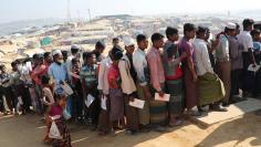 Rohingya refugees stand in a queue to collect aid supplies in Kutupalong refugee camp in Cox's Bazar