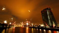 Fireworks explode in front of the skyline with the financial district and the European Central Bank (ECB, R) during New Year's eve celebrations in Frankfurt