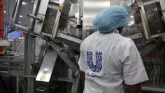 A woman stands behind a machine that is part of a toothpaste manufacturing line at the Unilever factory in Lagos