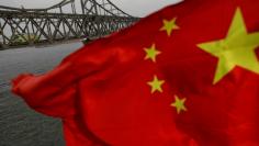 FILE PHOTO: A Chinese flag is seen in front of the Friendship bridge over the Yalu River connecting the North Korean town of Sinuiju and Dandong in China's Liaoning Province on April 1, 2017.  REUTERS/Damir Sagolj/File Photo