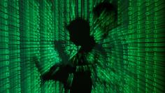 An illustration picture shows a projection of binary code on a man holding a laptop computer, in an office in Warsaw June 24, 2013. REUTERS/Kacper Pempel/Illustration/File Photo 