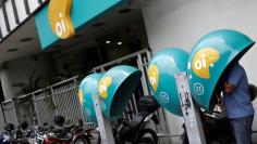 A man talks on a payphone with the logo of Brazilian telecoms company Oi SA outside the company's office in Rio de Janeiro