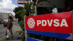 FILE PHOTO: A man walks past the corporate logo of the state oil company PDVSA at a gas station in Caracas, Venezuela December 1, 2017. REUTERS/Marco Bello/File Photo 