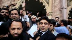 FILE PHOTO: Hafiz Saeed reacts to supporters as he walks out of court after a Pakistani court ordered his release from house arrest in Lahore