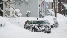 People help dig out a car from a parking spot after two days of record-breaking snowfall in Erie