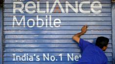 FILE PHOTO: A man opens the shutter of a shop painted with an advertisement of Reliance Communications in Mumbai, India, November 3, 2015.   REUTERS/Shailesh Andrade/File Photo