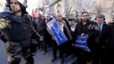 Iranian riot police stands guard as protesters hold street signs with the name of Shi'ite cleric Sheikh Nimr al-Nimr during a demonstration against the execution of Nimr in Saudi Arabia, outside the Saudi Arabian Embassy in Tehran