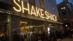 Passersby walk in front of the Shake Shack restaurant in the Manhattan borough of New York, December 29, 2014.  REUTERS/Keith Bedford 